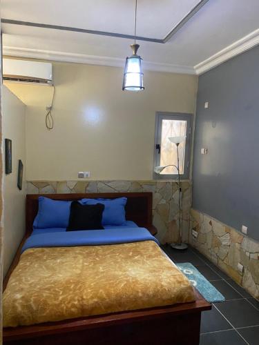 a bedroom with a large bed with blue pillows at Résidence H - Ekoumdoum in Yaoundé