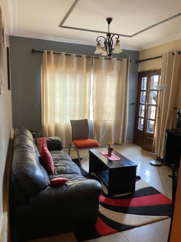 a living room with a leather couch and a coffee table at Résidence H - Ekoumdoum in Yaoundé