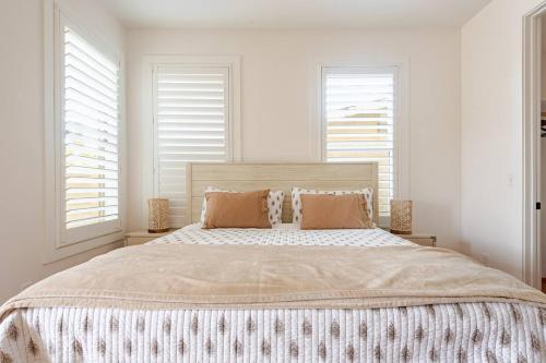 a bedroom with a large bed with white walls and windows at Private Encinitas Casita & Patio in Encinitas