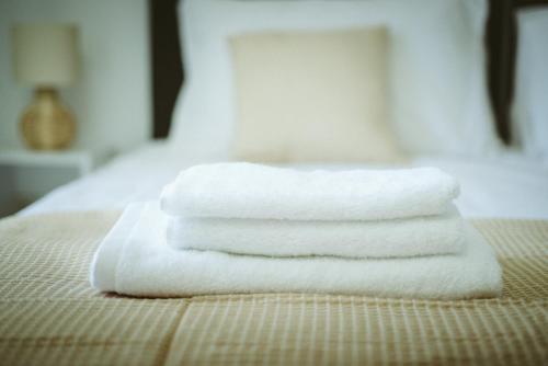a stack of white towels sitting on a bed at Sea Breeze Rooms in Armenistis