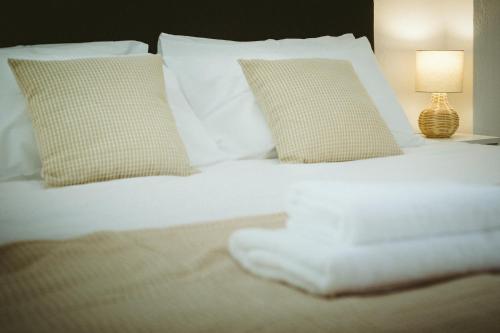 a bed with white sheets and pillows and a lamp at Sea Breeze Rooms in Armenistis
