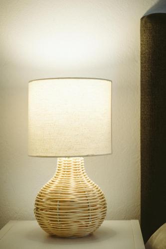 a lamp with a wicker lamp shade on a table at Sea Breeze Rooms in Armenistis
