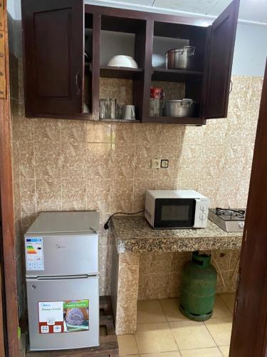 a small kitchen with a microwave and a refrigerator at Résidence H - Ekoumdoum in Yaoundé