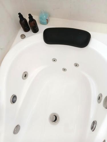 a white bath tub with a black paddle and shoes at Suíte Casal com Hidro no Centro - Infinito Particular in Guararema