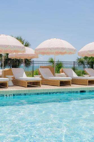 a pool with chairs and umbrellas next to the water at voco The Shelby - Myrtle Beach by IHG in Myrtle Beach