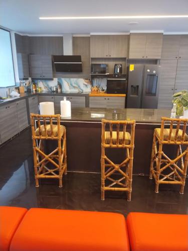 a kitchen with two chairs and a counter with an orange couch at Hermosa Nueva casa Moderna cerca de la Playa in Castelnovo