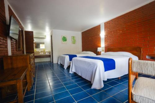 a room with three beds and a brick wall at Hotel Plaza Palmas in Tuxpan de Rodríguez Cano