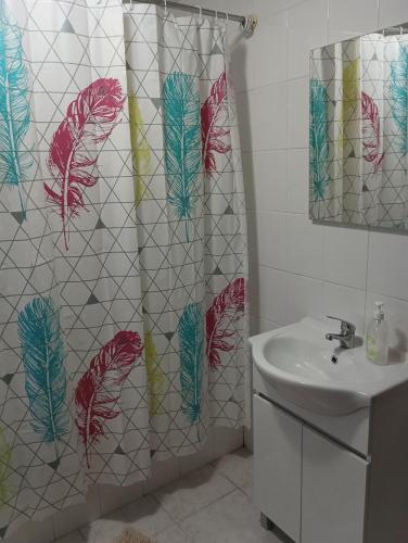 a bathroom with a shower curtain with feathers on it at Casa das Lezírias in Unhais da Serra