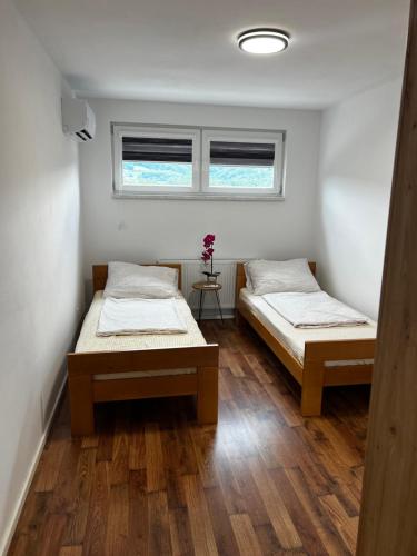 two beds in a room with a window at Apartman Nora in Teslić