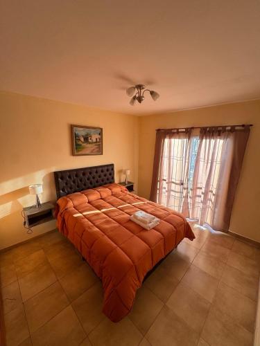 a bedroom with a bed with an orange blanket at Apart Dinkendein de 2 dormitorios in Río Cuarto