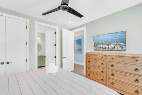a white bedroom with a ceiling fan and a wooden dresser at Emerald Tides - Luxury Oceanfront Home, Private Pool, 30' Dock in Marathon