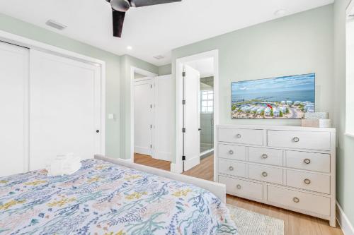 a white bedroom with a bed and a dresser at Emerald Tides - Luxury Oceanfront Home, Private Pool, 30' Dock in Marathon