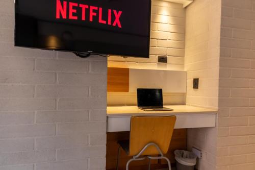 a tv hanging on a wall with a laptop on a desk at Terra Biohotel in Medellín