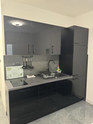 Una cocina con gabinetes negros y un fregadero. en Borak Apartmani, en Sutivan