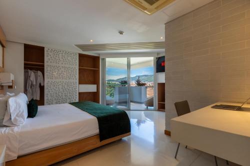 a bedroom with a bed and a desk and a view at Terra Biohotel in Medellín