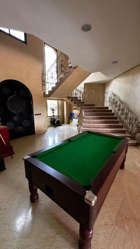 a pool table in the middle of a room with stairs at Ma ferme in Dar Mouddene