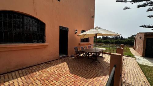 a patio with a table and an umbrella at Ma ferme in Dar Mouddene