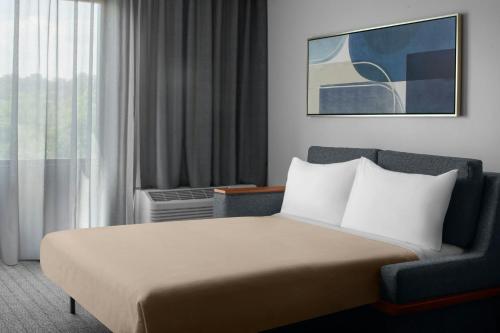 a bedroom with a bed and a chair and a window at Courtyard Pittsburgh Settlers Ridge/Robinson Township in Robinson Township