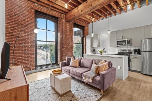 a living room with a couch and a brick wall at Brick & Bed Riverfront Lofts, G 202 in Saint Louis