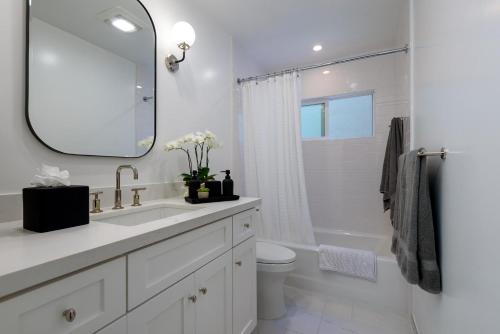 a bathroom with a sink and a toilet and a mirror at The Cove at Rincon by Paradise Retreats in Carpinteria