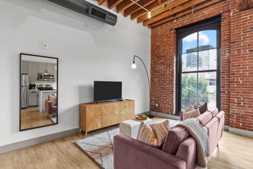 a living room with two chairs and a brick wall at Brick & Bed Riverfront Lofts, G 202 in Saint Louis