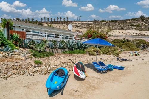 a beach with two kayaks and an umbrella and a boat at The Cove at Rincon by Paradise Retreats in Carpinteria