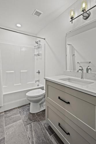 a white bathroom with a toilet and a sink at Brick & Bed Riverfront Lofts, G 202 in Saint Louis