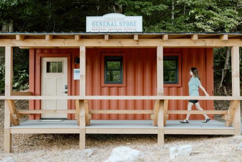 a woman walking in front of a orange building at Farmhouse Tiny home with fishing Pond - Oak Cabin in Gatlinburg