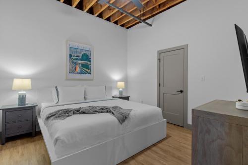 Un dormitorio blanco con una gran cama blanca y dos mesas. en Stay in Style! Stunning River View - King Bed, en Saint Louis