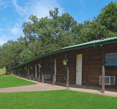 a wooden building with a green lawn in front of it at Hotel room #5 in Madill