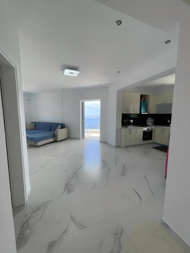 a white living room with a blue couch and marble floors at Endless blue Apartments in Dhërmi