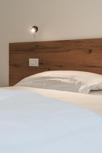 a bedroom with a white bed with a wooden headboard at Casa Stefania 2 in Pieve Di Ledro