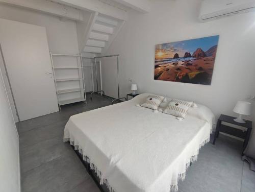 a white bedroom with a large bed and a painting on the wall at Casa Tabarka in Carloforte