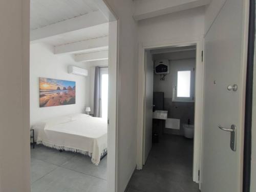 a white bedroom with a bed and a bathroom at Casa Tabarka in Carloforte