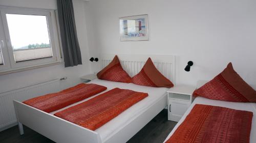 two beds in a room with red pillows at Gästehaus Mira in Winterberg