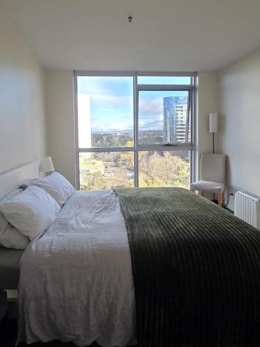 a bedroom with a bed and a large window at The Metropolitan Apartments in Canberra
