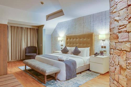 a hotel room with a bed and a chair at La Abbey Hotel and Suites in Mama
