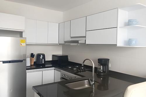 a kitchen with white cabinets and a black counter top at Apartamento Vacacional sky/el Rodadero in Santa Marta