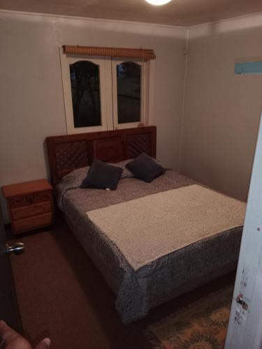 ein Schlafzimmer mit einem Bett mit zwei Kissen und einem Fenster in der Unterkunft Cabaña Arte Patagonia in Puyehue
