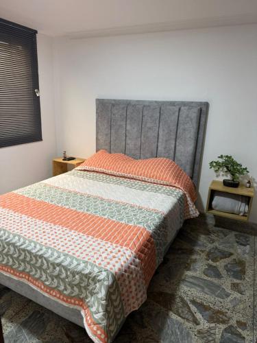 a bedroom with a bed with an orange and white quilt at Hermoso apartamento en guayabal in Medellín
