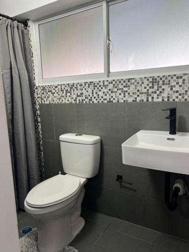 a bathroom with a toilet and a sink and a window at Fats Place - Pedro Clisante in Sosúa