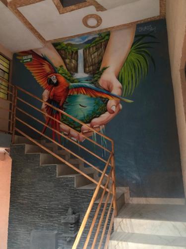 a staircase with a painting of a person holding a parrot at Hostal California AC-DC in Baños