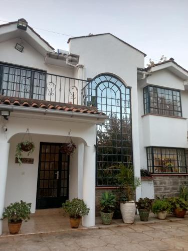 Casa blanca con ventanas negras y macetas en Rhino Villas, Karen, en Nairobi