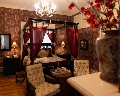a bedroom with a canopy bed with red curtains at Silver Heart Inn & Cottages in Independence