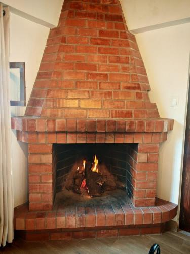 a brick fireplace with a fire in it at Casa de campo Asikuy House in Urubamba