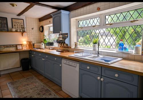 eine Küche mit blauen Schränken, einem Waschbecken und einem Fenster in der Unterkunft Beautiful apartment at field view cottage in Eccleston