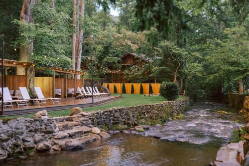 a backyard with a rock wall and a river at Tiny Home Firepit BBQ Fishing Willow Cabin in Gatlinburg