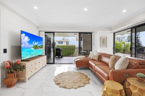 a living room with a couch and a flat screen tv at Oceanfront Luxe 2BR in Bargara