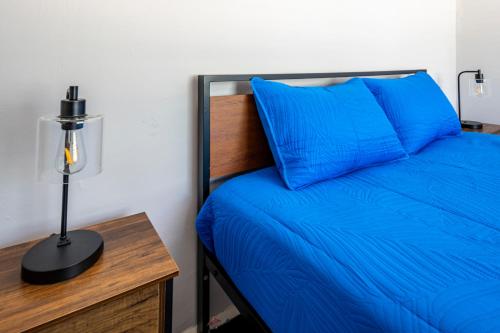 a bed with blue sheets and a desk with a lamp at Cozy 2BR Retreat with Workspace - Washer and Dryer in Kettering