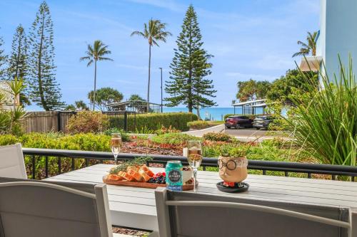 a table with a tray of food and glasses of wine at Oceanfront Luxe 3BR in Bargara